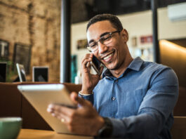 Live-Chat, Social Media, Avatare: Die Vielfalt der digitalen Kundenkommunikation Ein junger POC telefoniert und hat ein Tablet in der Hand.