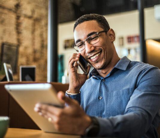 Live-Chat, Social Media, Avatare: Die Vielfalt der digitalen Kundenkommunikation Ein junger POC telefoniert und hat ein Tablet in der Hand.