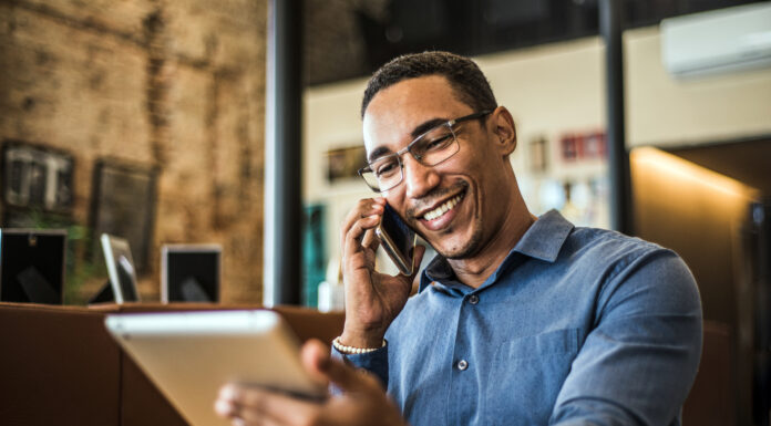 Live-Chat, Social Media, Avatare: Die Vielfalt der digitalen Kundenkommunikation Ein junger POC telefoniert und hat ein Tablet in der Hand.