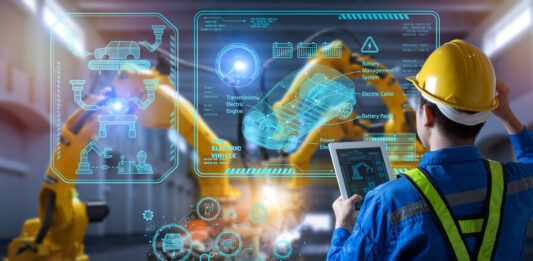 Arbeitsabläufe modern gestalten durch Prozessdigitalisierung Ein Mann steht vor einer Glaswand in der Produktion.