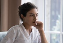 5 Gründe, warum Frauen 2024 noch immer finanzielle Nachteile haben Junge Frau sitzt nachdenklich am Schreibtisch