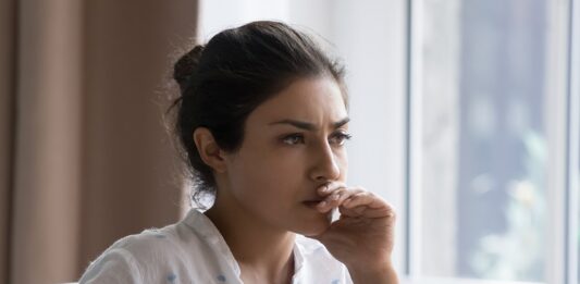 5 Gründe, warum Frauen 2024 noch immer finanzielle Nachteile haben Junge Frau sitzt nachdenklich am Schreibtisch