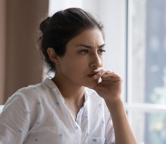 5 Gründe, warum Frauen 2024 noch immer finanzielle Nachteile haben Junge Frau sitzt nachdenklich am Schreibtisch