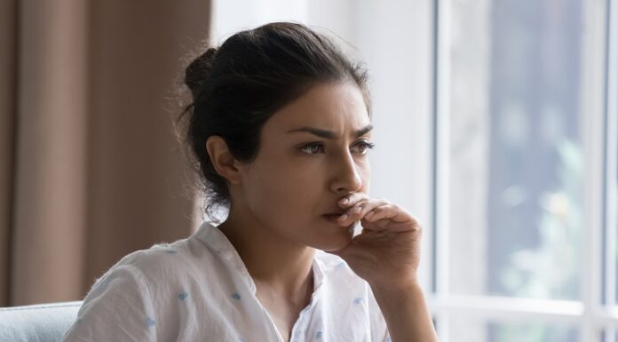 5 Gründe, warum Frauen 2024 noch immer finanzielle Nachteile haben Junge Frau sitzt nachdenklich am Schreibtisch