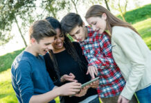 Erfolgreich in die Zukunft investieren – das Planspiel Börse der Förde Sparkasse Gruppe von Teeangern schaut gemeinsam auf ein Tablet