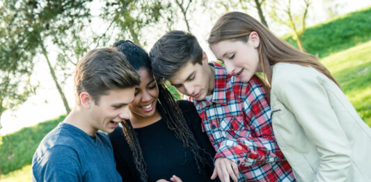 Erfolgreich in die Zukunft investieren – das Planspiel Börse der Förde Sparkasse Gruppe von Teeangern schaut gemeinsam auf ein Tablet