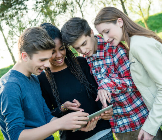 Erfolgreich in die Zukunft investieren – das Planspiel Börse der Förde Sparkasse Gruppe von Teeangern schaut gemeinsam auf ein Tablet