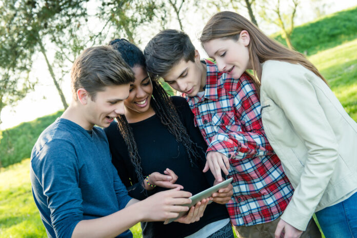 Gruppe von Teeangern schaut gemeinsam auf ein Tablet