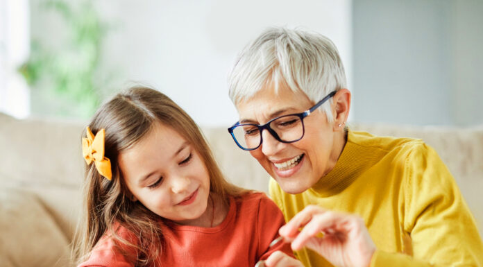 Vermögensbarometer 2024: Die finanzielle Zufriedenheit steigt wieder Großmutter und ihre Enkelin werfen Geld in ein pinkes Sparschwein.