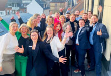 Quereinstieg bei der Förde Sparkasse Viele Frauen und Männer schauen jubelnd auf einem Gruppenbild in die Kamera.