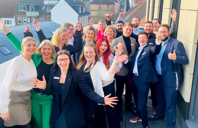 Viele Frauen und Männer schauen jubelnd auf einem Gruppenbild in die Kamera.