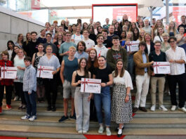 Netrace – Die Internetralley für Schüler:innen Gruppe von Schülerinnen und Schülern, die auf einer Treppe stehen und Plakate mit Gewinnsummen hochhalten.