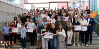 Netrace – Die Internetralley für Schüler:innen Gruppe von Schülerinnen und Schülern, die auf einer Treppe stehen und Plakate mit Gewinnsummen hochhalten.