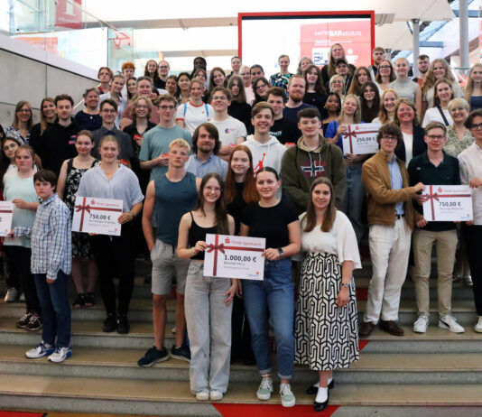 Netrace – Die Internetralley für Schüler:innen Gruppe von Schülerinnen und Schülern, die auf einer Treppe stehen und Plakate mit Gewinnsummen hochhalten.