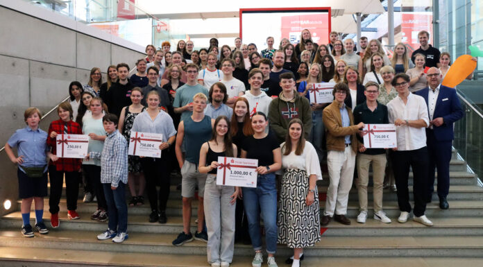 Netrace – Die Internetralley für Schüler:innen Gruppe von Schülerinnen und Schülern, die auf einer Treppe stehen und Plakate mit Gewinnsummen hochhalten.
