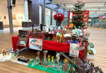 Lotties Welt: Über 90 Wünsche bei der Aktion „Wunschbaum“ Ein Fliegenpilz Maskottchen steht hinter einem Tisch voller Basteleien von Kindern, im Hintergrund ein Weihnachtsbaum