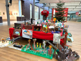 Lotties Welt: Über 90 Wünsche bei der Aktion „Wunschbaum“ Ein Fliegenpilz Maskottchen steht hinter einem Tisch voller Basteleien von Kindern, im Hintergrund ein Weihnachtsbaum