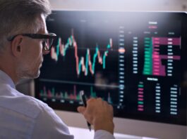 Alles, was Sie über die Market Cap wissen sollten Trader sitzt vor einem Bildschirm auf dem ein Börsenchart sichtbar ist.