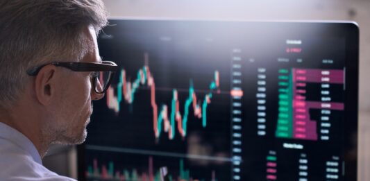 Alles, was Sie über die Market Cap wissen sollten Trader sitzt vor einem Bildschirm auf dem ein Börsenchart sichtbar ist.