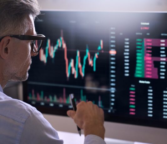 Alles, was Sie über die Market Cap wissen sollten Trader sitzt vor einem Bildschirm auf dem ein Börsenchart sichtbar ist.