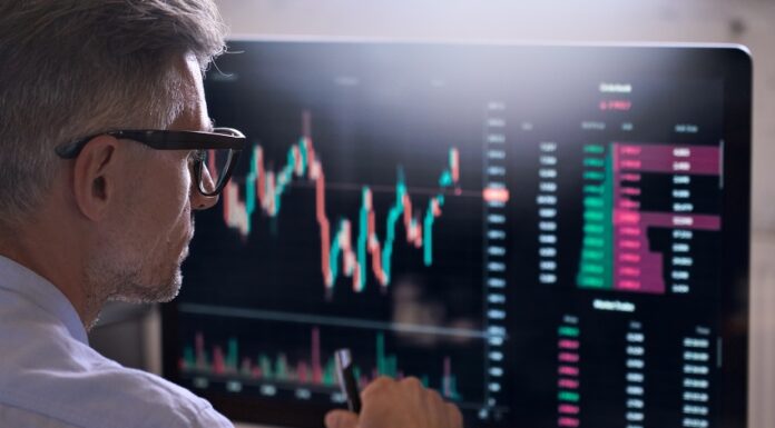 Alles, was Sie über die Market Cap wissen sollten Trader sitzt vor einem Bildschirm auf dem ein Börsenchart sichtbar ist.