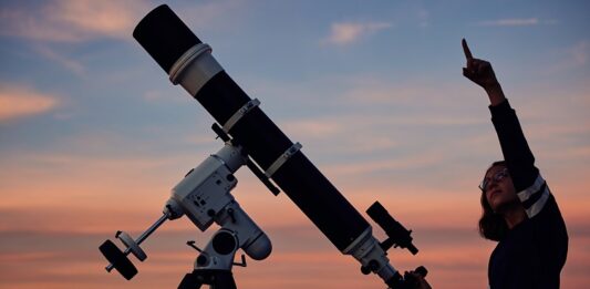 Chancen und Risiken im Börsenjahr 2025 Frau zeigt in den Himmel vor einem Teleskop