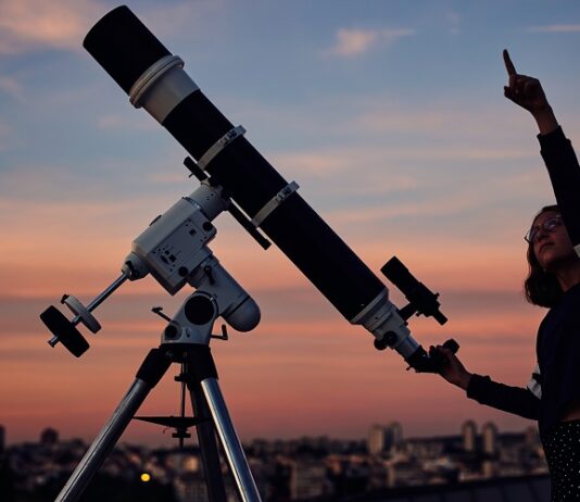 Chancen und Risiken im Börsenjahr 2025 Frau zeigt in den Himmel vor einem Teleskop