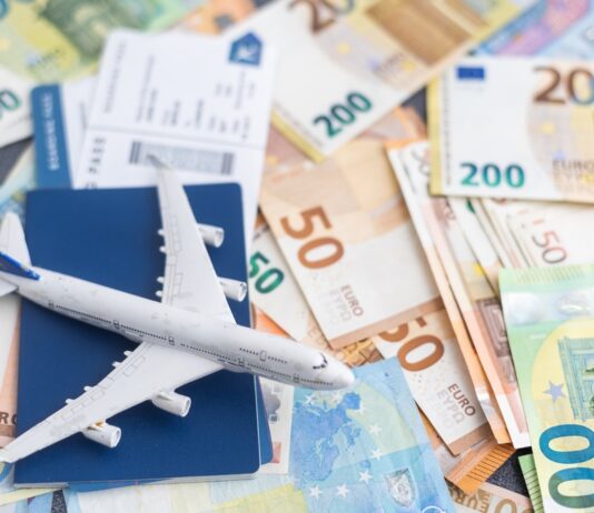 Flugpreise steigen 2025 Kleines Spielzeugflugzeuge steht auf mehreren Euro-Banknoten und einem Flugticket.