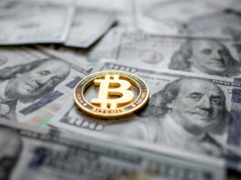 Bitcoin: Zwischen Rallye und Risiken Goldene Bitcoin Münze liegt auf mehreren 100-Dollar-Scheinen.