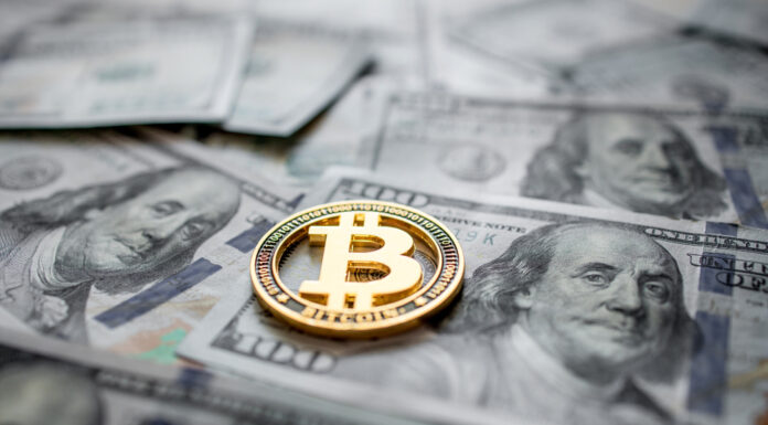 Bitcoin: Zwischen Rallye und Risiken Goldene Bitcoin Münze liegt auf mehreren 100-Dollar-Scheinen.