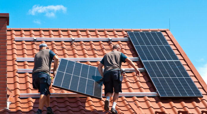 Photovoltaik: Wann sich Strom vom Dach lohnt Zwei Arbeiter installieren eine Solarzelle auf einem roten Ziegeldach.