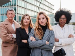 Gender Pay Gap: Darum sollten sich Frauen früh für ein gutes Gehalt stark machen Vier Geschäftsfrauen verschiedenen Alters und verschiedener Herkunft stehen mit verschränkten Armen nebeneinander und schauen entschlossen nach vorn.