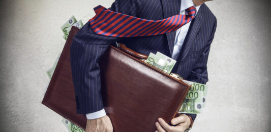 Wie groß ist 1 Million Euro? Ein Businessmann mit einem Aktenkoffer, aus dem 100-Euro-Scheine rausfallen.