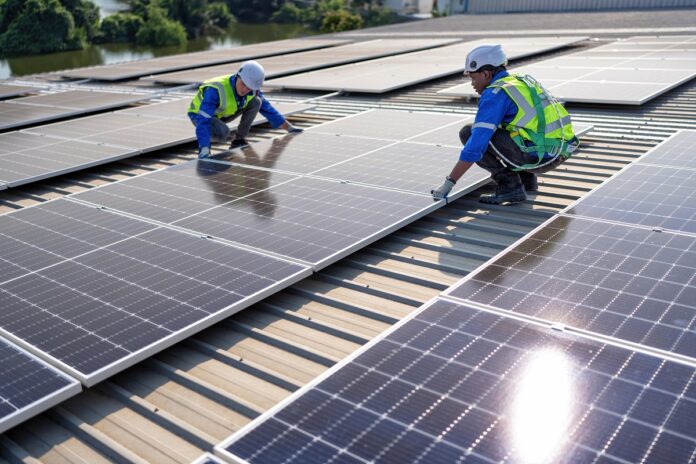 Zwei Arbeiter installieren eine Solarzelle auf einem Dach.