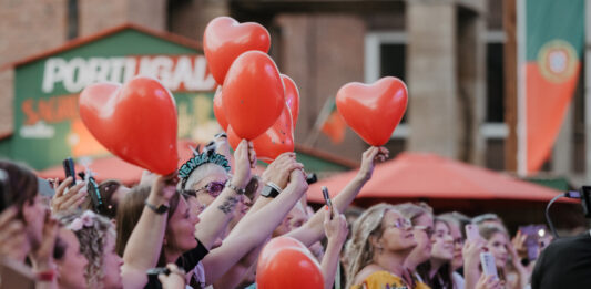 Kieler Woche: Weniger Zeit fürs Bezahlen, mehr Zeit fürs Feiern Menschen feiern mit roten Ballons in den Händen auf einem Konzert der Rathausbühne der Kieler Woche