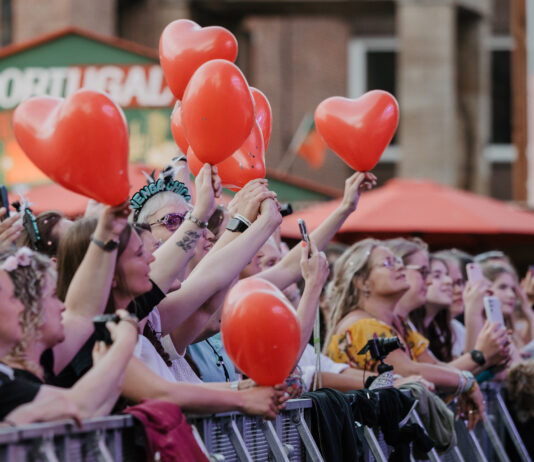 Kieler Woche: Weniger Zeit fürs Bezahlen, mehr Zeit fürs Feiern Menschen feiern mit roten Ballons in den Händen auf einem Konzert der Rathausbühne der Kieler Woche