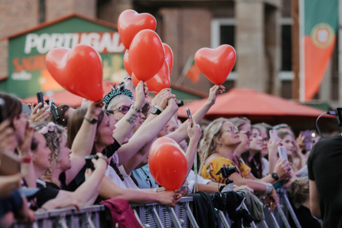 Menschen feiern mit roten Ballons in den Händen auf einem Konzert der Rathausbühne der Kieler Woche