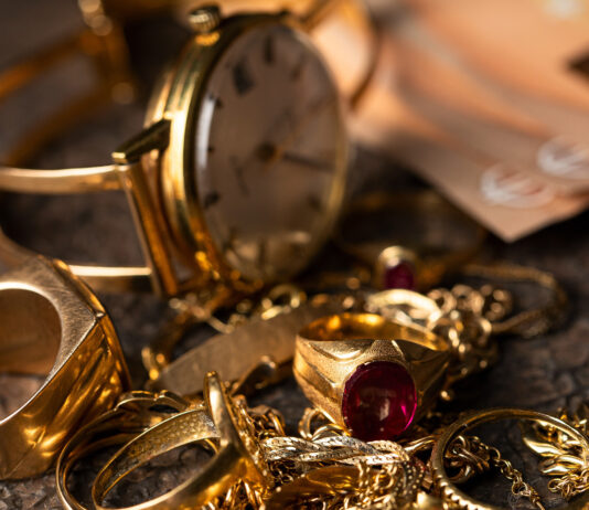 So viel Geld bekommen Sie für alten Schmuck Eine alte Uhr und Ketten und Ringe aus Gold liegen auf einem Haufen, im Hintergrund sind 50-Euro-Scheine zu sehen