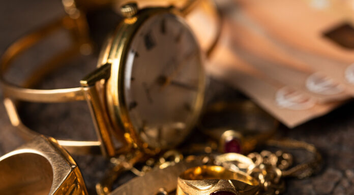 So viel Geld bekommen Sie für alten Schmuck Eine alte Uhr und Ketten und Ringe aus Gold liegen auf einem Haufen, im Hintergrund sind 50-Euro-Scheine zu sehen