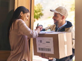 Paket kaputt, verschwunden oder bei Nachbar:innen – Wer haftet wann? Eine Frau nimmt vom Paketboten ein Paket an und unterschreibt dafür.