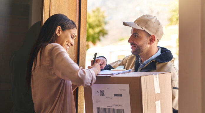 Paket kaputt, verschwunden oder bei Nachbar:innen – Wer haftet wann? Eine Frau nimmt vom Paketboten ein Paket an und unterschreibt dafür.