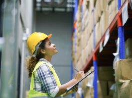 Supply-Chain-Management: Lieferketten krisensicher aufstellen Eine Frau mit Sicherheitsweste und Bauhelm überprüft den Lagerbestand mit einem Klemmbrett