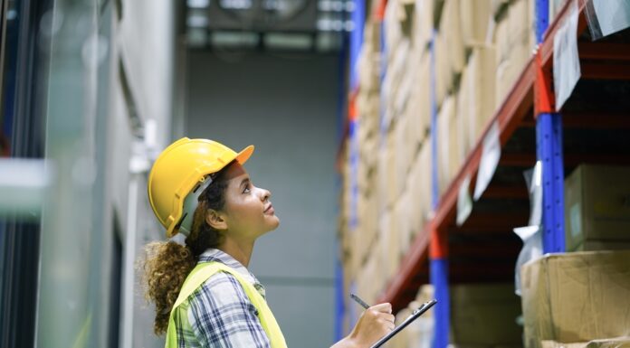 Supply-Chain-Management: Lieferketten krisensicher aufstellen Eine Frau mit Sicherheitsweste und Bauhelm überprüft den Lagerbestand mit einem Klemmbrett