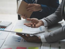 Unternehmensbewertung: So ermitteln Sie den Wert Ihres Unternehmens Zwei Männer analysieren Geschäftsfinanzberichte