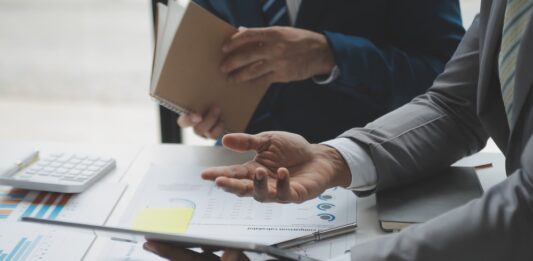 Unternehmensbewertung: So ermitteln Sie den Wert Ihres Unternehmens Zwei Männer analysieren Geschäftsfinanzberichte