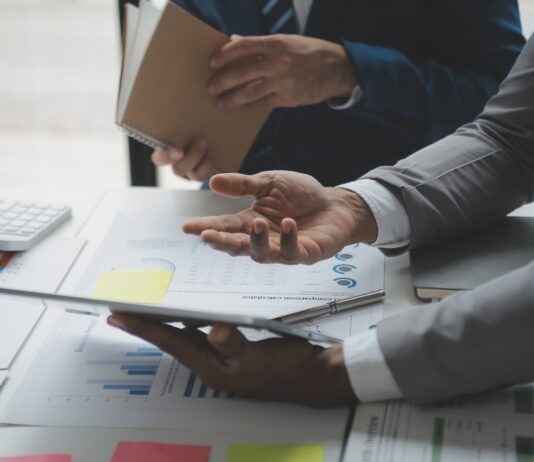 Unternehmensbewertung: So ermitteln Sie den Wert Ihres Unternehmens Zwei Männer analysieren Geschäftsfinanzberichte