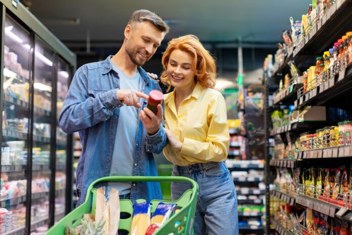 Spouses,Buying,Food,In,Supermarket,,Discussing,And,Choosing,Products,,Standing