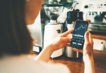 Rekord: 14 Millionen investierten 2025 in Aktienanlagen Frau schaut auf Handy mit Aktienkurs auf dem Display