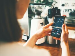 Rekord: 14 Millionen investierten 2025 in Aktienanlagen Frau schaut auf Handy mit Aktienkurs auf dem Display