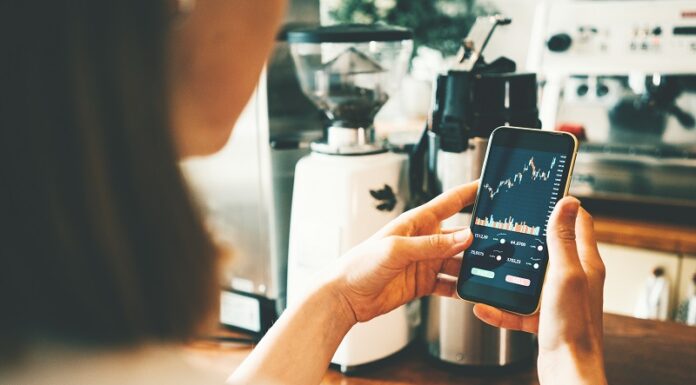 Rekord: 14 Millionen investierten 2025 in Aktienanlagen Frau schaut auf Handy mit Aktienkurs auf dem Display